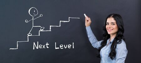 Next level concept with young woman writing on a blackboardの写真素材