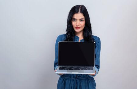 Young woman with a laptop computer on a gray backgroundの写真素材
