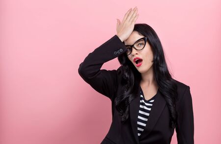 Young woman making a mistake on a pink backgroundの写真素材