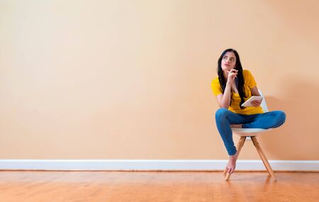 Young woman using her tablet sitting in a chairの写真素材