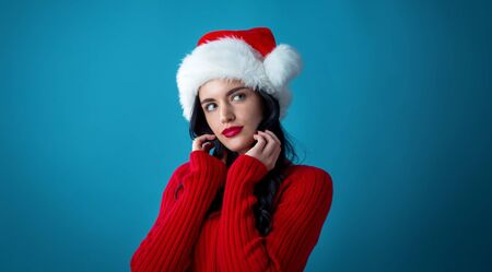 Young woman with Santa hat thoughtful pose on a dark blue backgroundの写真素材