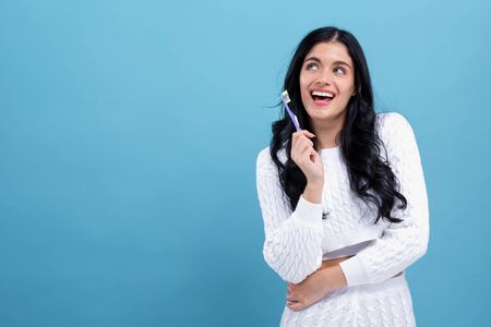 Young woman holding a toothbrush on a blue background