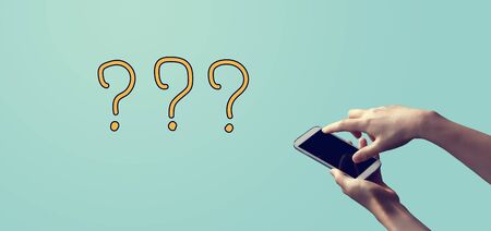 Question marks with person holding a white smartphoneの写真素材