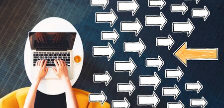 Arrow going in a opposite direction with person using a laptop on a white table Gold bird ornament in a snow covered landscapeの写真素材