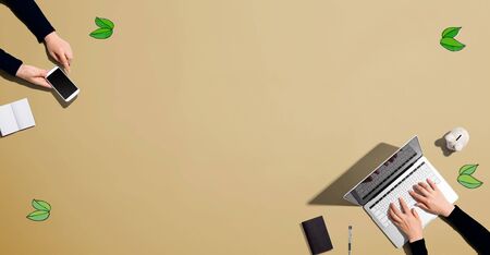 Green leaves with people working together with laptop and phoneの写真素材