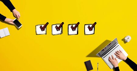 Checklist with people working together with laptop and phoneの写真素材