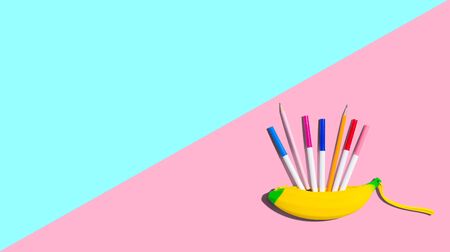 Banana shaped pen case with colorful pens and pencilsの写真素材