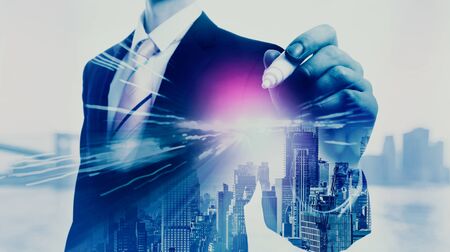 Businessman holidng a pen on a city backgroundの写真素材