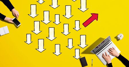 Arrow going in a different direction with people working together with laptop and phone