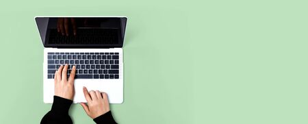 Person using a laptop computer on a solid color background
