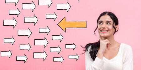 Arrow going in the opposite direction with young woman in thoughtful poseの写真素材