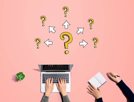 Big and small question marks with arrows with people working together with laptop and notebookの写真素材