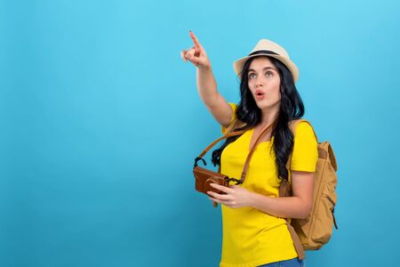 Young woman pointing while hiking on a blue backgroundの写真素材