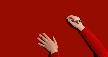 Person writing something with a pen from above