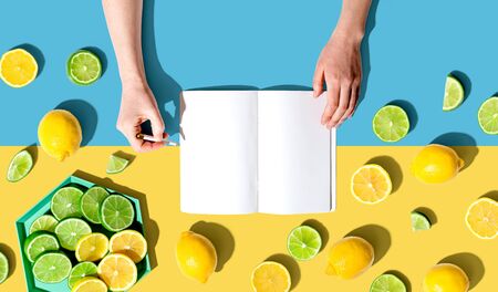 Person writing in a notebook with lemons and limes