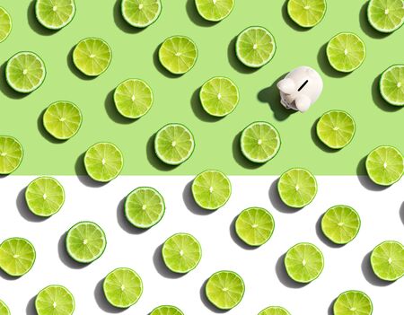 One out unique piggy bank surrounded by limes - flat layの写真素材