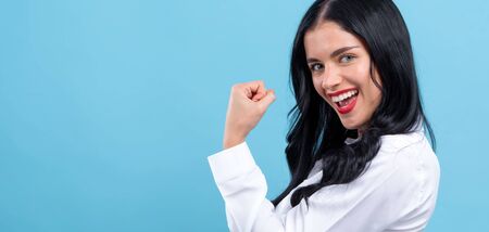Powerful young woman in a success pose on a blue backgroundの写真素材