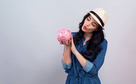 Young woman with a piggy bank on a gray backgroundの写真素材