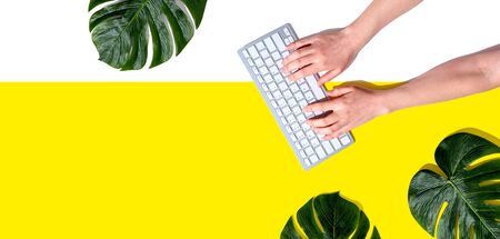 Person using a computer keyboard with tropical leaves from above