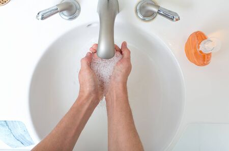Person washing their hands at with soap and water for coronavirus preventionの写真素材