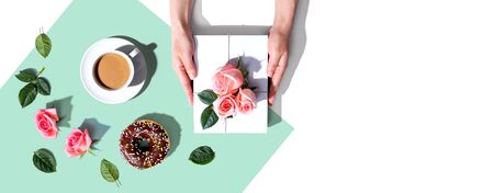 Female hands holding a gift box with pink roses overhead view - flat layの写真素材