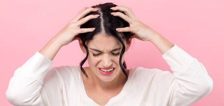 Young woman suffering from headache on a pink backgroundの写真素材