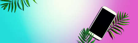 Smartphone with tropical palm leaves - flat lay