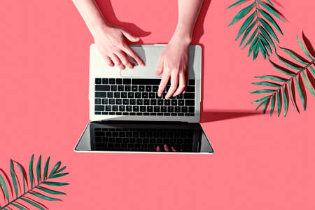 Person using a laptop computer with tropical leaves from above