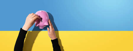 Person depositing money in a pink piggy bankの写真素材