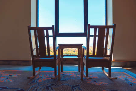 Rustic rocking chairs silhouetted against scenic autumn mountainsの写真素材