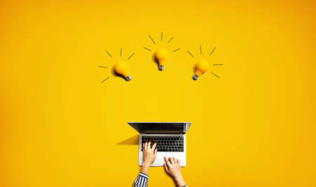 Person using a laptop computer with three light bulbs from aboveの写真素材