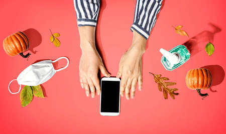 Smartphone with a mask and a sanitizer bottle in Autumnの写真素材