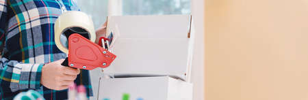 Young woman packing boxes to be shipped in her home officeの写真素材