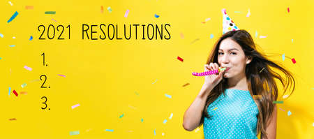 2021 Resolutions with young woman with party theme on a yellow backgroundの写真素材