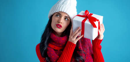 Young woman holding a gift box on a dark blue background