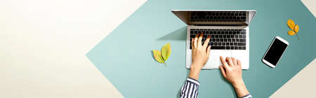 Autumn leaves with person using a laptop computer from above