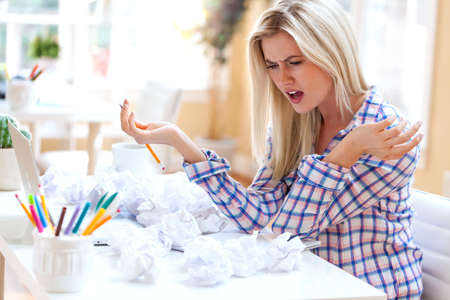 Frustrated woman with crumpled paper balls in her home officeの写真素材