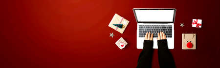 Person using a laptop computer with Christmas gift boxes from aboveの写真素材