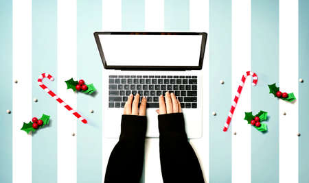 Person using a laptop computer with Christmas decorations from aboveの写真素材