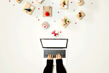 Person using a laptop computer with Christmas gift boxes from above