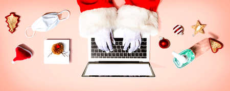 Santa Claus using a laptop computer with a mask and a sanitizer bottle from aboveの写真素材