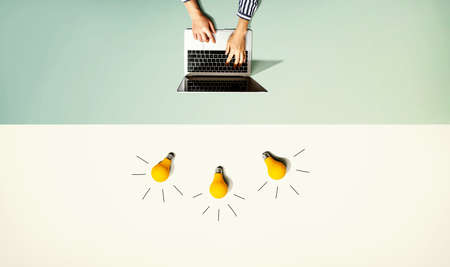 Person using a laptop computer with three light bulbs from aboveの写真素材