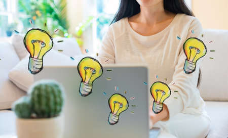 Light bulbs with woman using her laptop in her home office