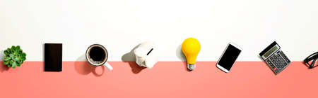 Office supplies with a piggy bank and a lightbulb - flat layの写真素材