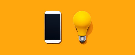 Smartphone with a yellow light bulb from aboveの写真素材