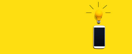 Smartphone with a yellow light bulb from aboveの写真素材