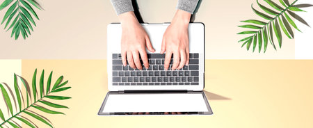 Person using a laptop computer with tropical leavesの写真素材