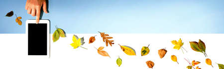 Autumn leaves with person using a tablet computerの写真素材