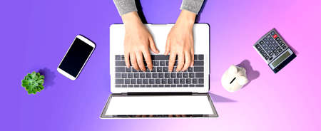 Woman using a laptop computer with a piggy bankの写真素材