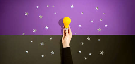 Person holding a yellow light bulb with stars